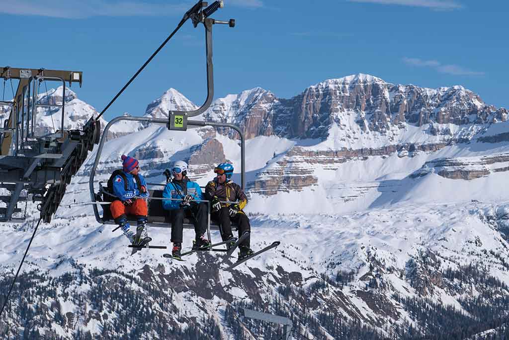 Three skiers on the chairlift in Pinzolo in Alta Val Rendena